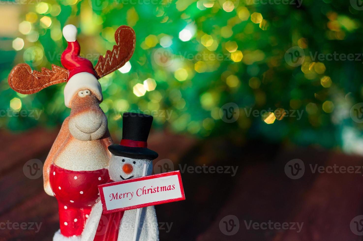 Natale alce con un' pupazzo di neve in piedi su un' sfocato sfondo Natale albero foto