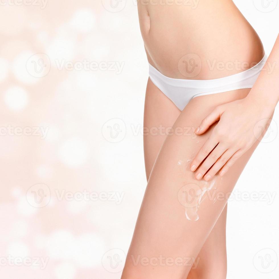 donna l'applicazione cosmetico idratante crema su corpo foto