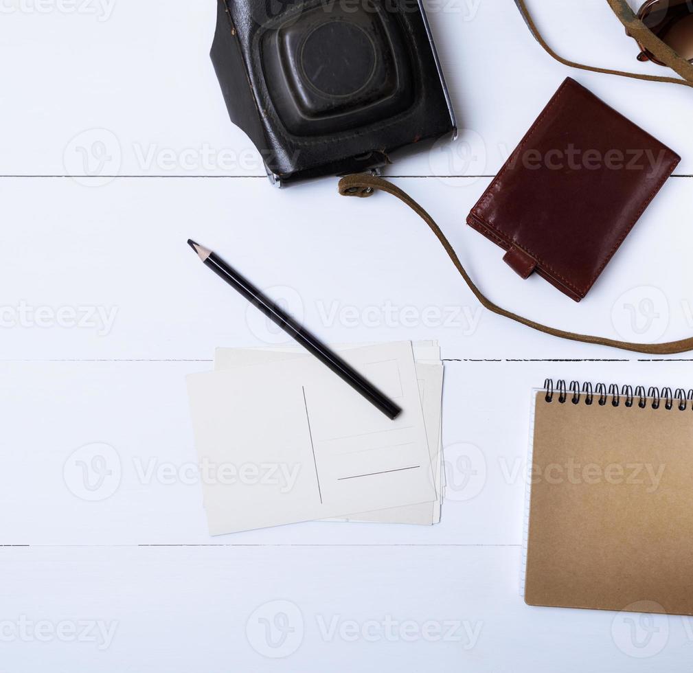 vuoto carta cartoline e un' nero di legno matita su un' bianca di legno sfondo, accanto un' Marrone pelle borsa foto