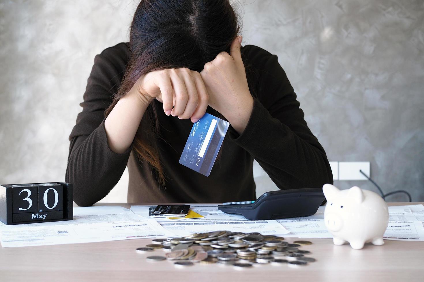 un' giovane donna con un' credito carta debito e molti fatture posto su il tavolo. foto