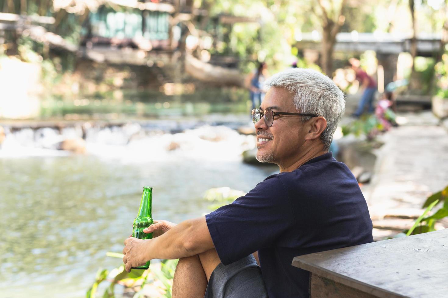 contento uomo con Sorridi mano Tenere imbottigliare di birra con nuture all'aperto. foto