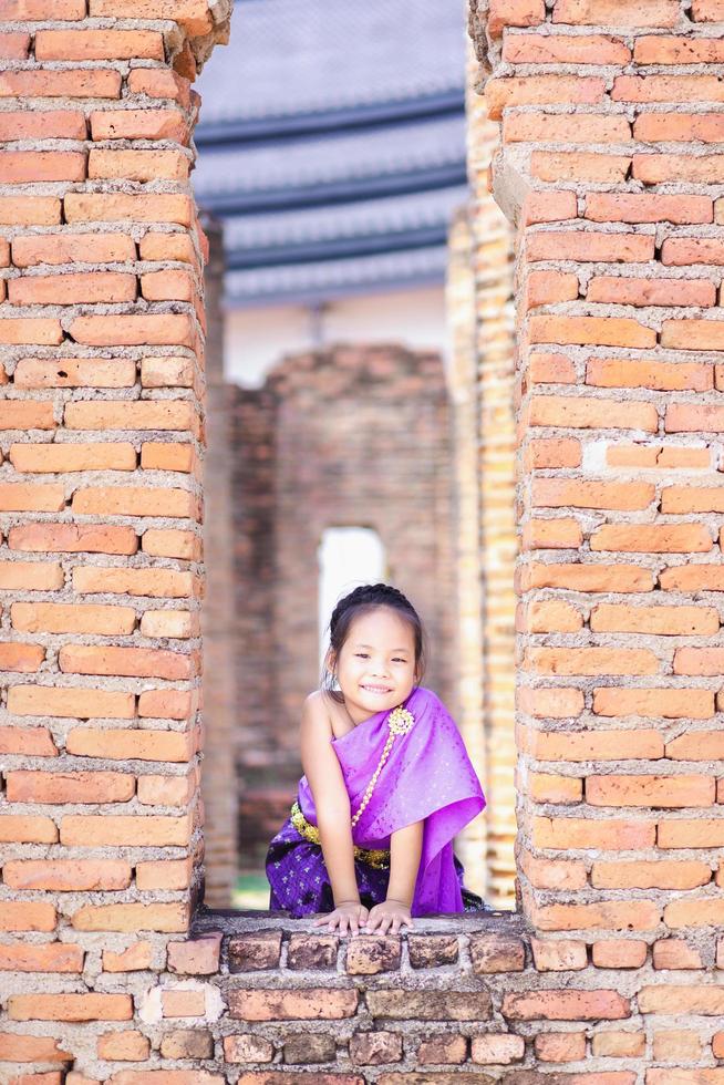 piccola ragazza asiatica in abito d'epoca tailandese in piedi in resti antichi foto
