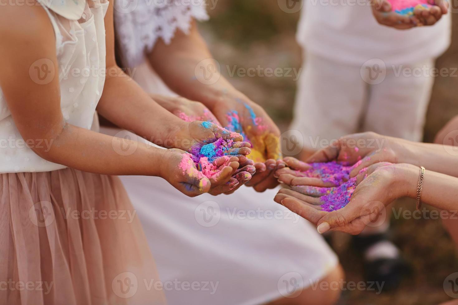 mani di bambini e adulti nel il colori di il sala. famiglia avendo divertimento con holi vernici all'aperto. holi colore Festival foto