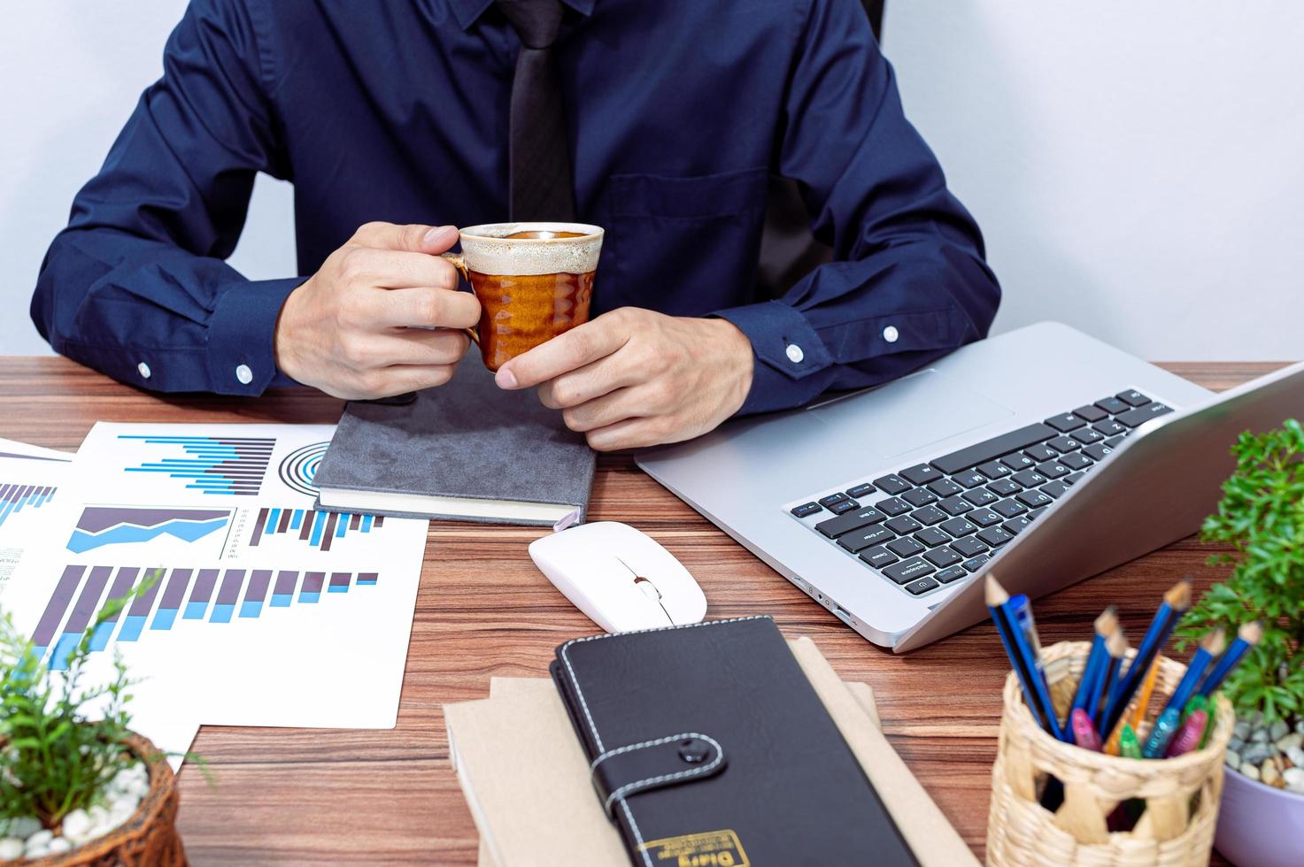 uomo d'affari che beve caffè alla sua scrivania foto