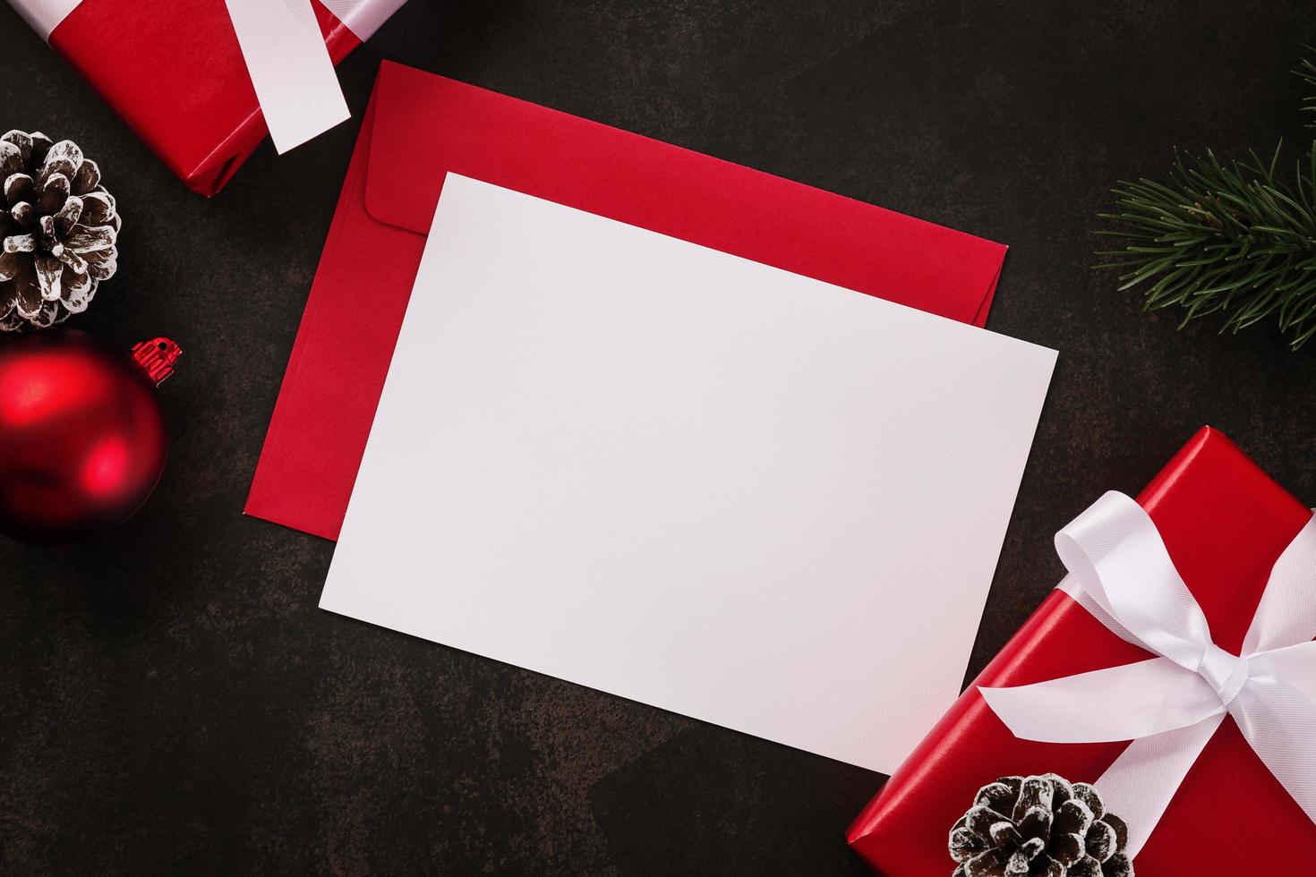 biglietto di auguri bianco vuoto e mockup di busta con decorazioni di regali di Natale su sfondo grunge foto