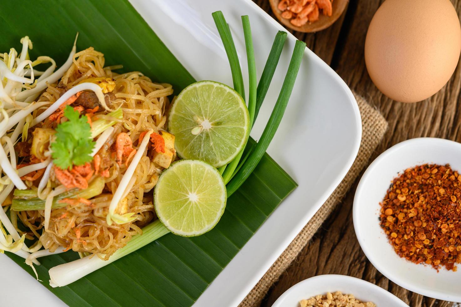 pad thai con limone, uova e condimento su un tavolo di legno foto