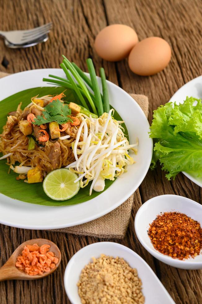 pad thai con limone, uova e condimento su un tavolo di legno foto