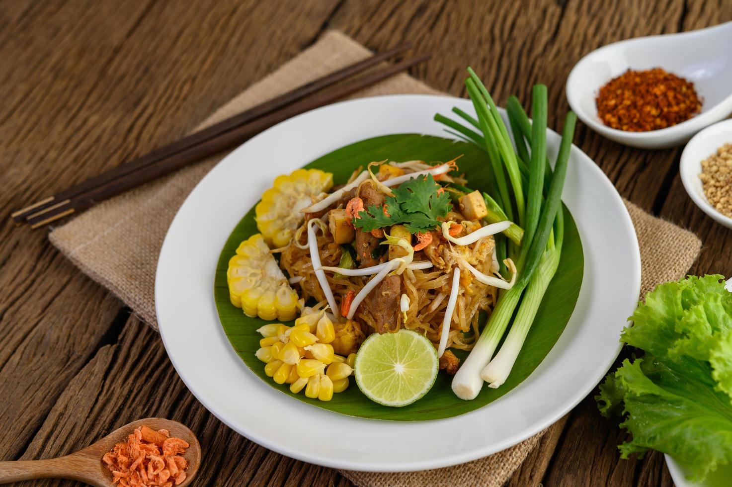 pad thai con limone, uova e condimento su un tavolo di legno foto