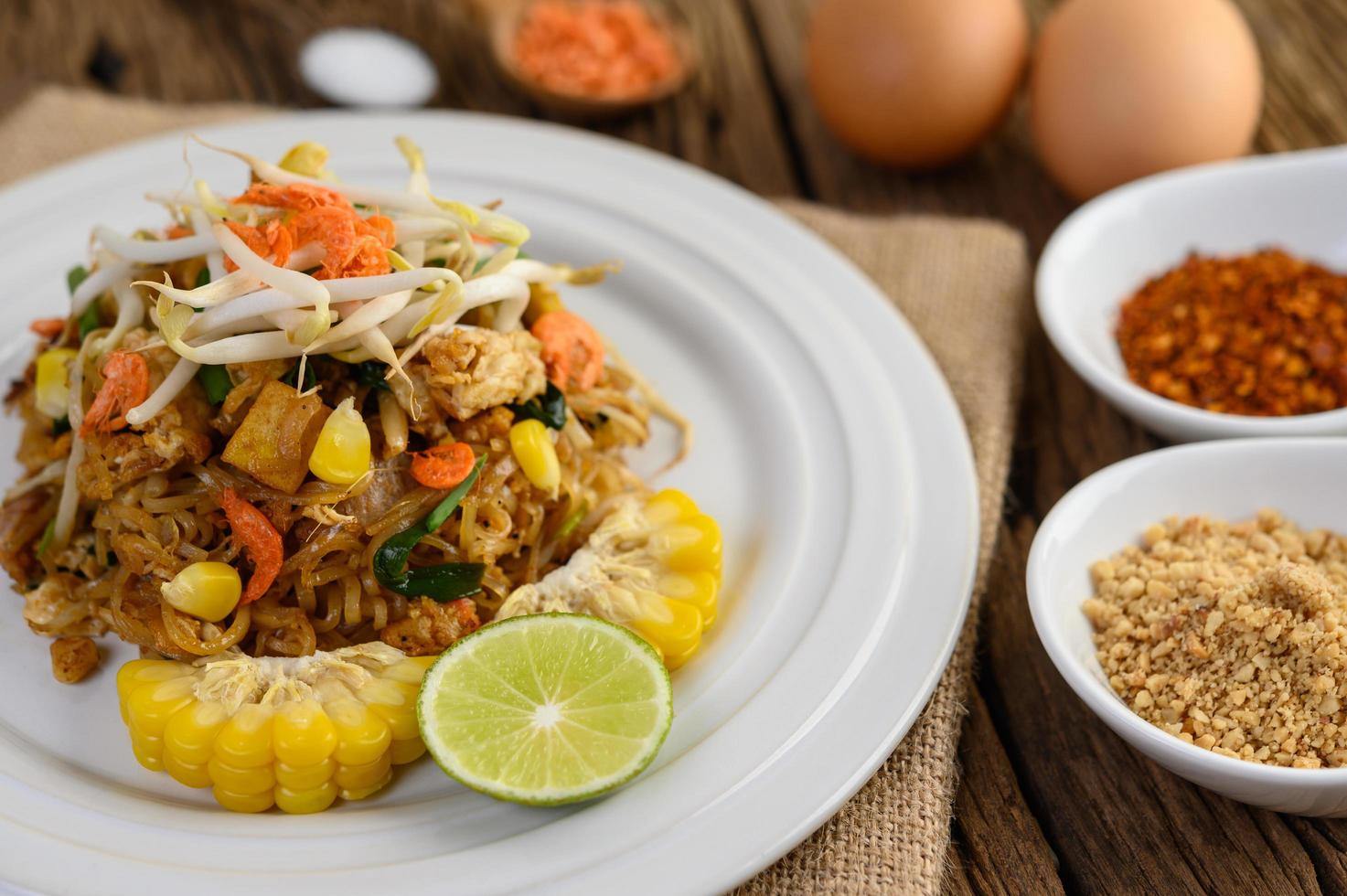 pad thai con limone, uova e condimento su un tavolo di legno foto