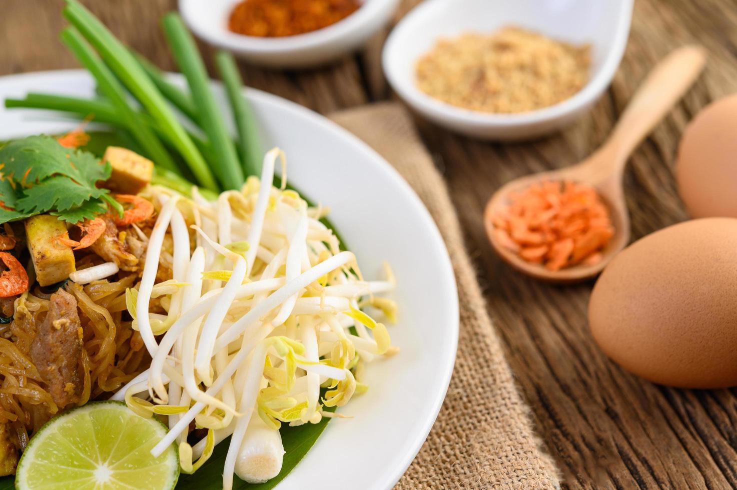 pad thai con limone, uova e condimento su un tavolo di legno foto