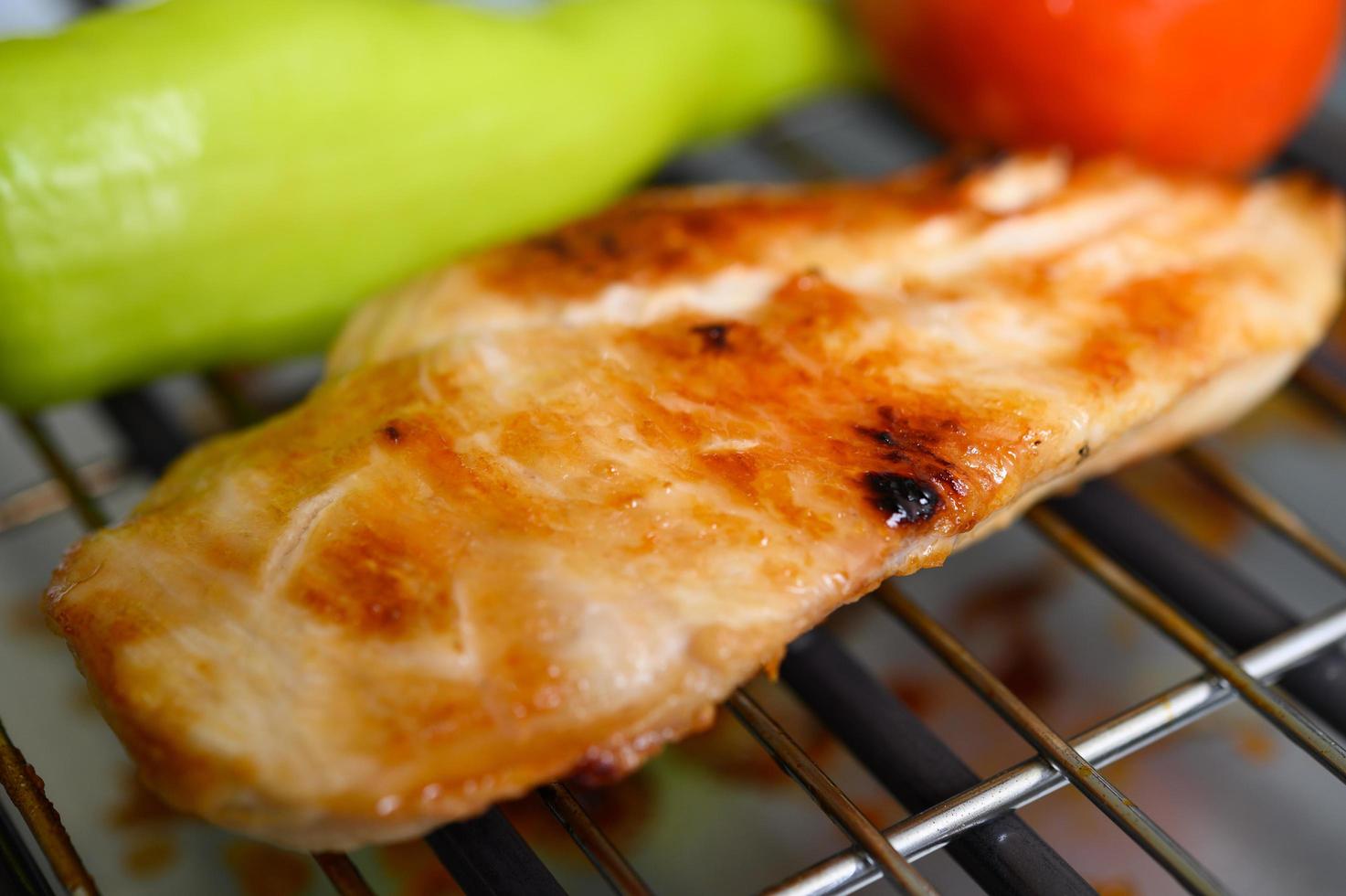 petto di pollo alla griglia su una griglia elettrica con paprika e pomodoro foto