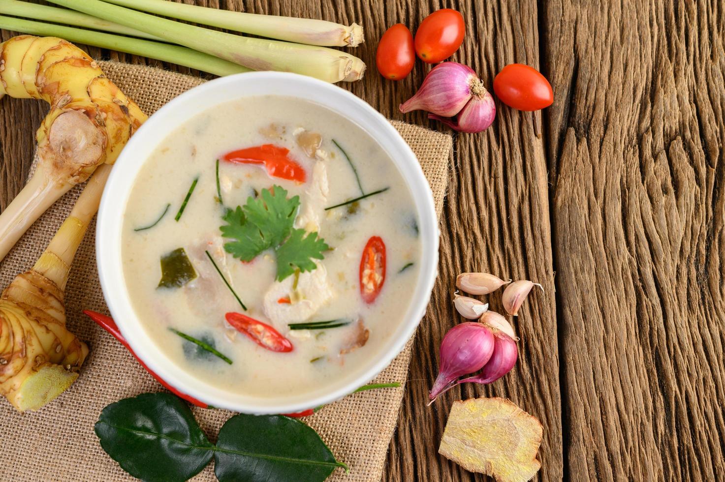 tom kha kai, zuppa di cocco tailandese sul bordo della cucina in legno foto