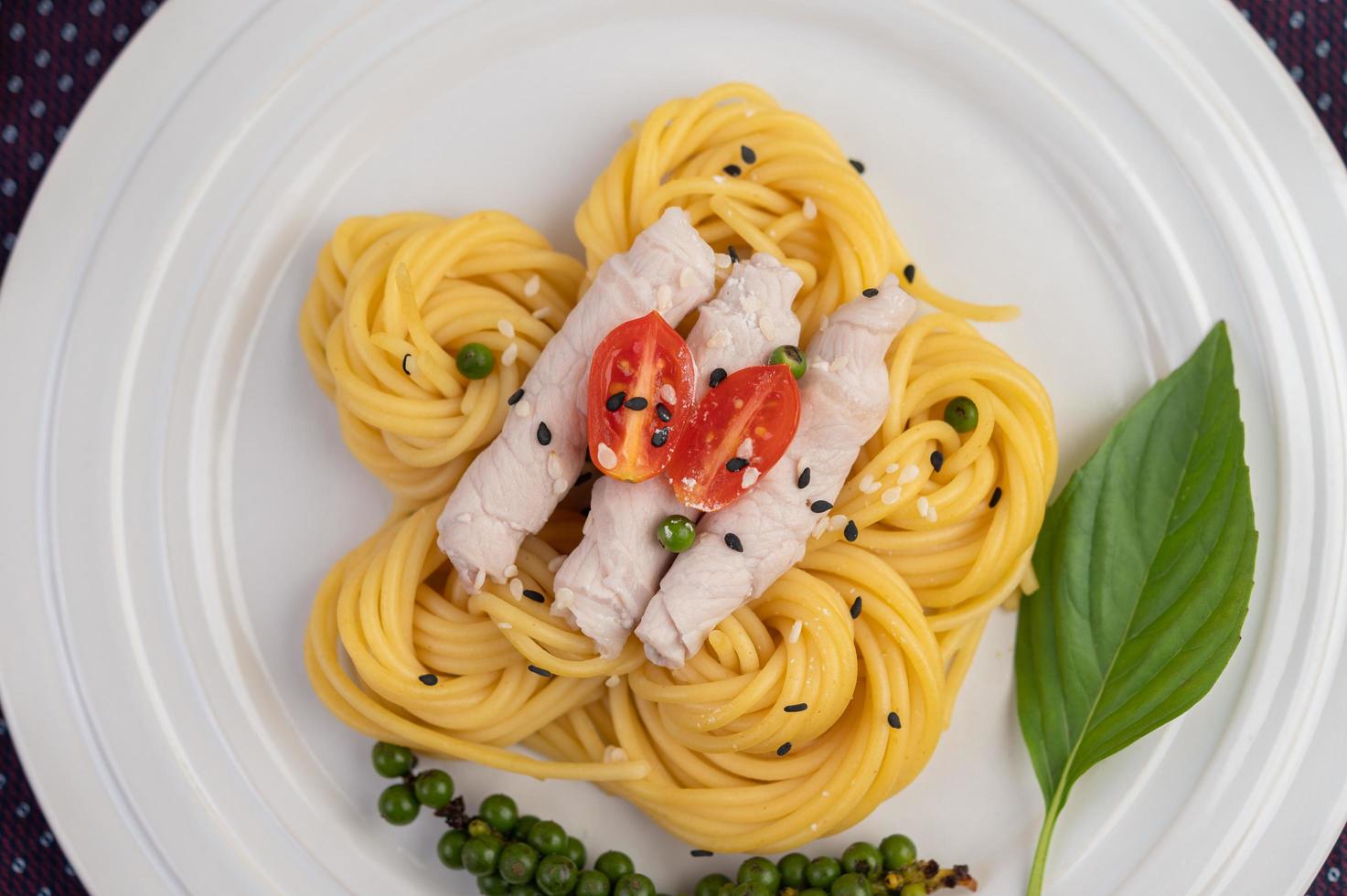 spaghetti e carne di maiale placcati disposti su un piatto bianco foto