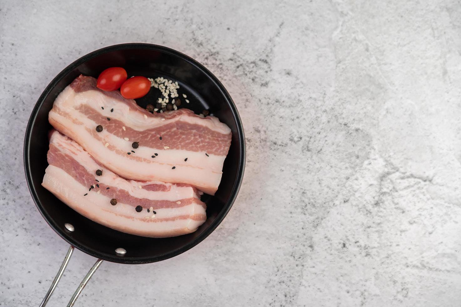 pancetta di maiale in padella con semi di pepe, pomodori e spezie foto