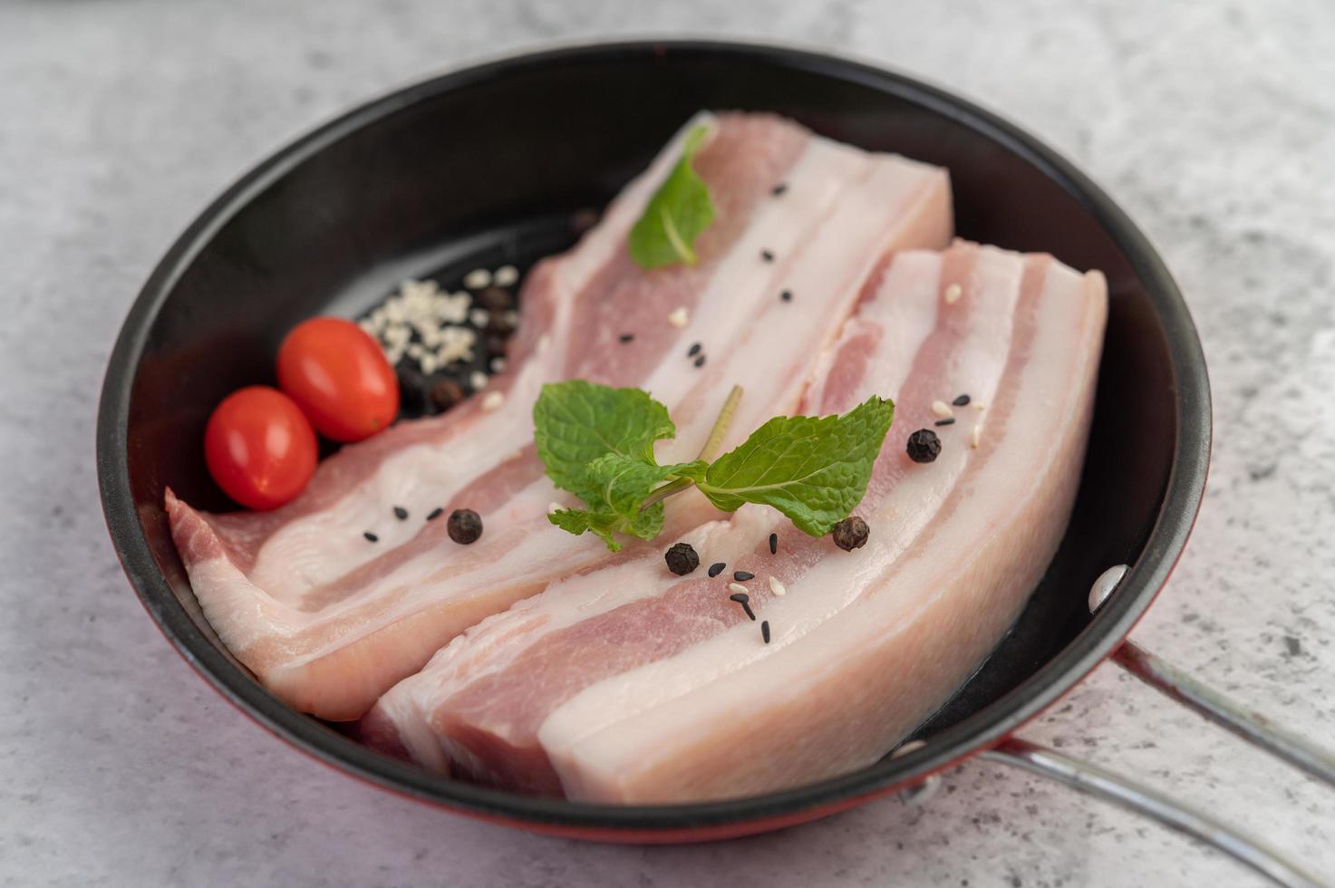 pancetta di maiale in padella con semi di pepe, pomodori e spezie foto