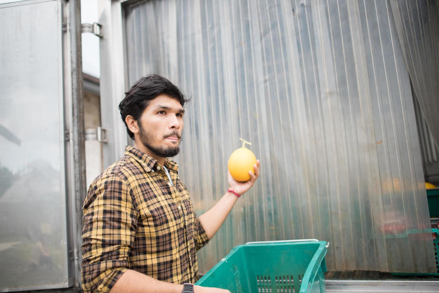 ritratto di un contadino hipster tenendo la scatola di frutta per la vendita sul mercato foto