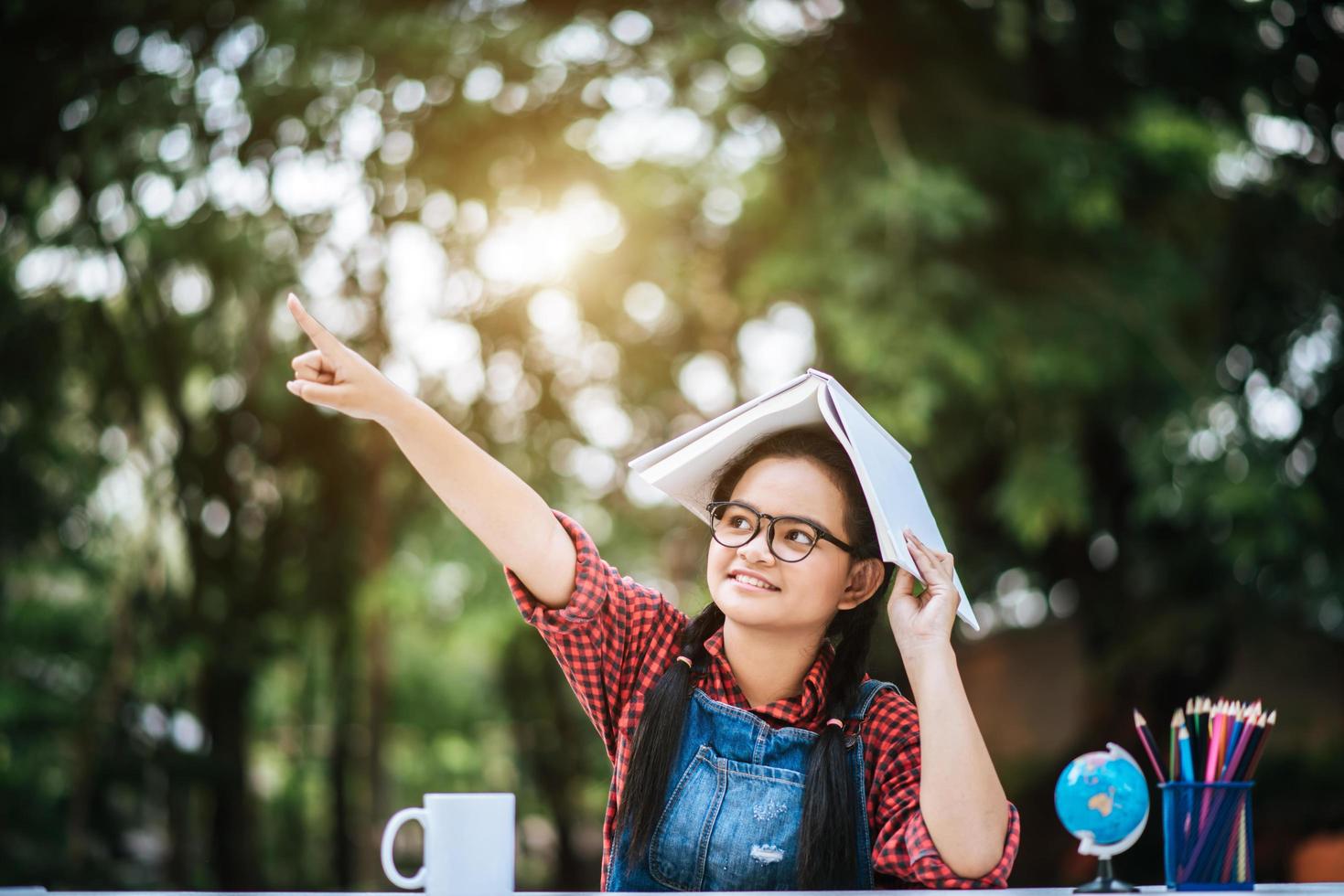 giovane ragazza con il libro sopra la sua testa nel parco foto