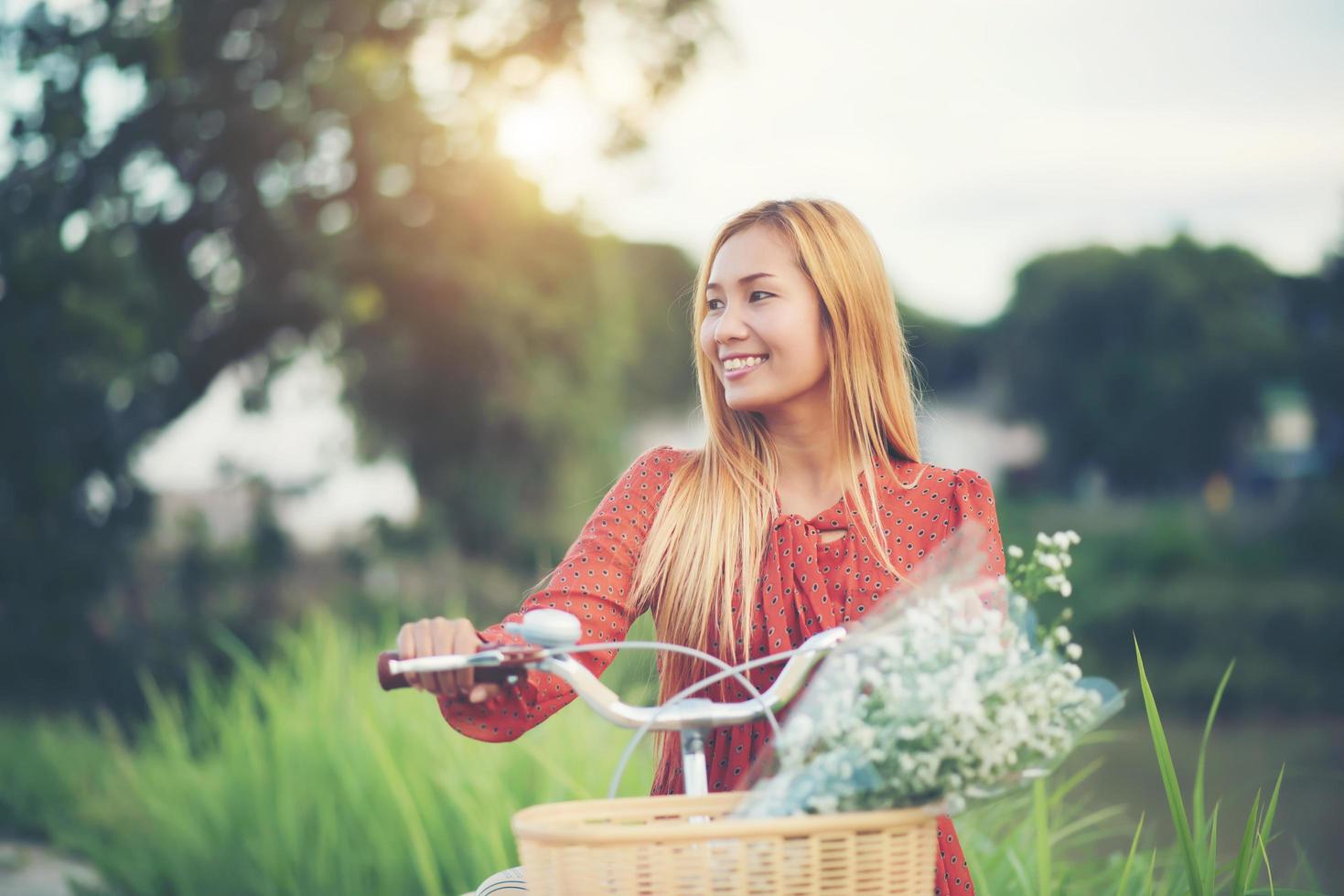 giovane donna asiatica in sella a una bicicletta in un parco foto