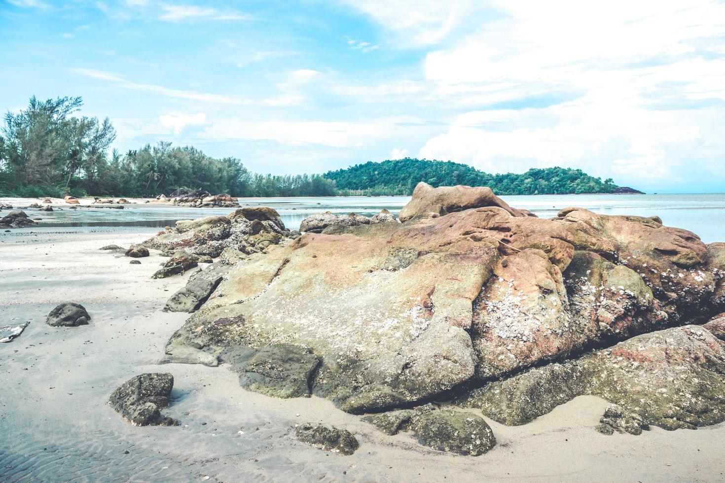 rocce sulla spiaggia con cielo blu nuvoloso foto