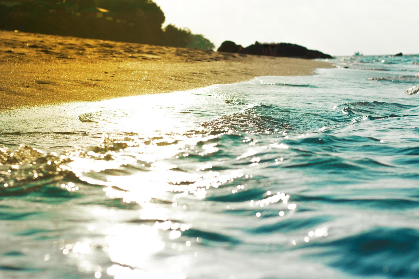 sabbia e acqua in spiaggia con cielo blu chiaro foto