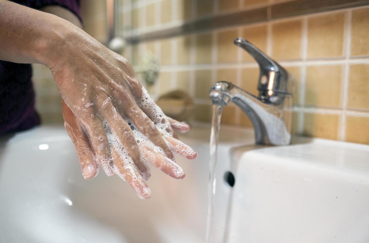 persona che si lava le mani in bagno foto