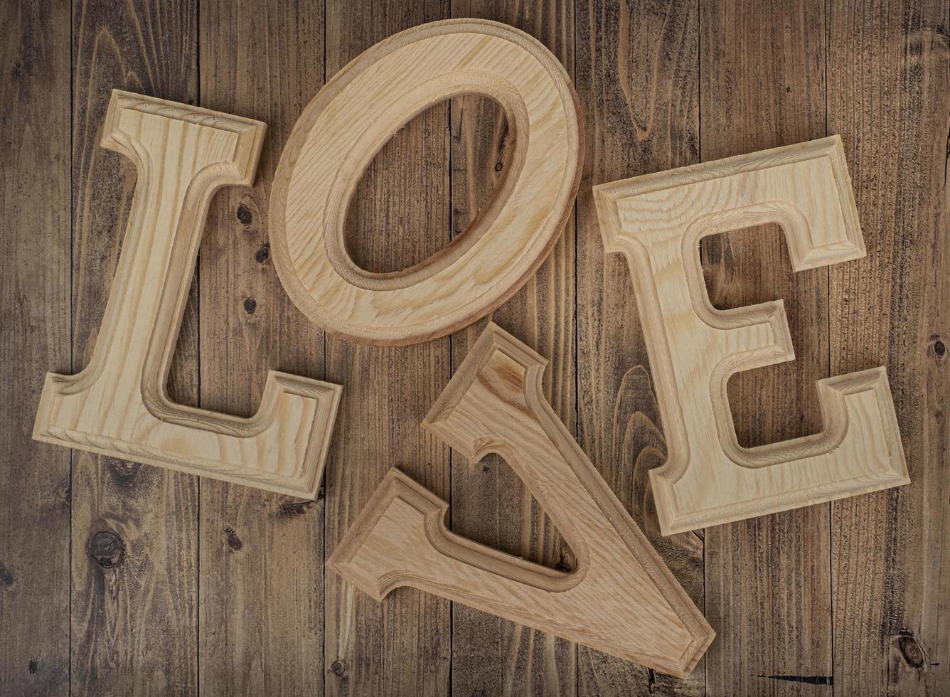 lettere in legno disordinate che formano la parola amore su uno sfondo di legno di noce. concetto di st. San Valentino foto