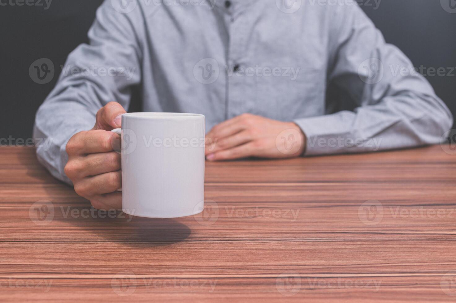 uomo che tiene una tazza di caffè alla sua scrivania foto