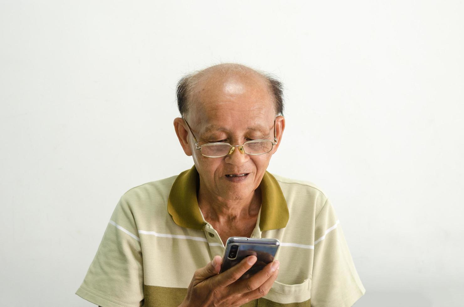 vecchio guardando il suo telefono cellulare foto