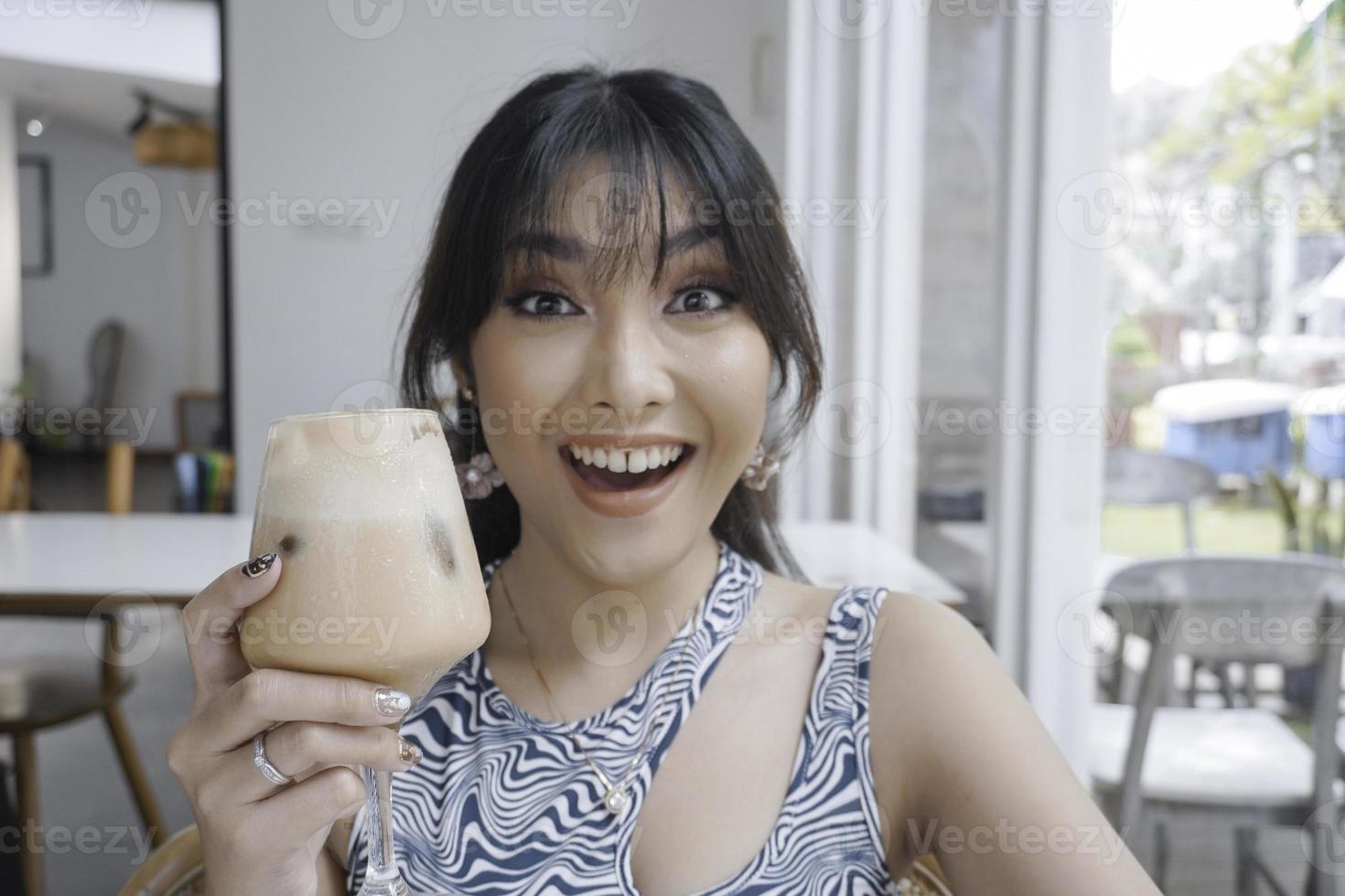 vicino su ragazza è potabile caffè. lei ha caffè schiuma su sua labbra e lei sorrisi. lei è godendo sua mattina cappuccino. foto