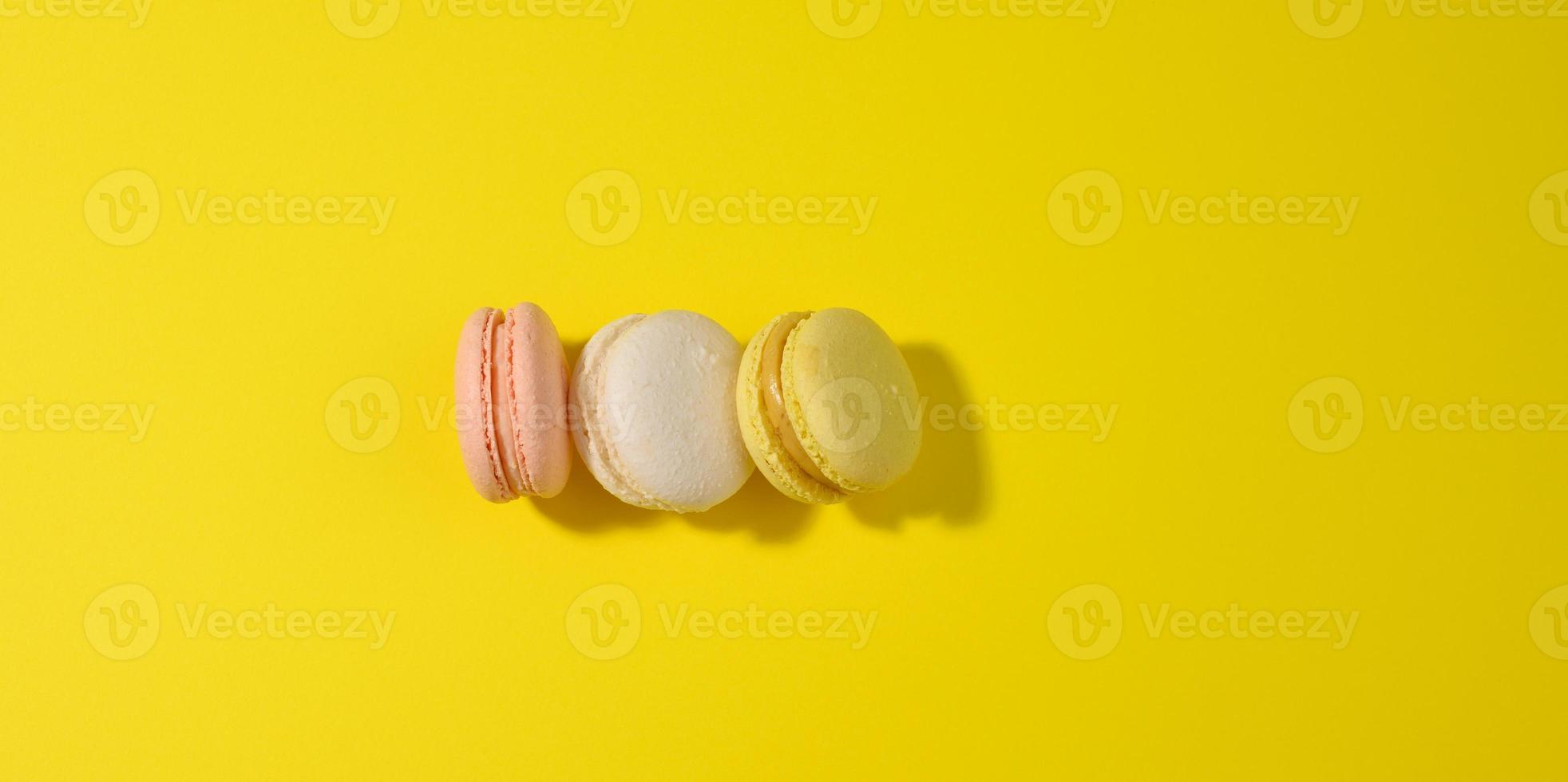 il giro multicolore macarons su un' giallo sfondo con un' ombra su un' giallo sfondo foto