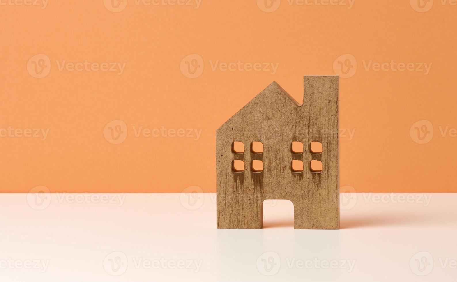 Marrone di legno Casa su un' arancia sfondo. vero tenuta noleggio, Acquista e vendita concetto. agente immobiliare Servizi, edificio riparazione e Manutenzione foto