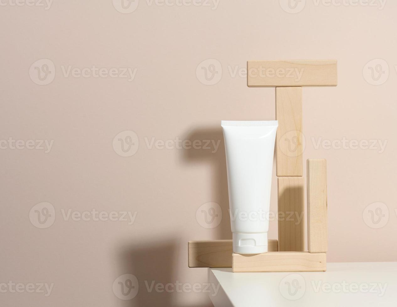 vuoto bianca plastica tubi per cosmetici su un' beige sfondo con di legno blocchi. confezione per crema, gel, siero, pubblicità e Prodotto promozione, finto su foto