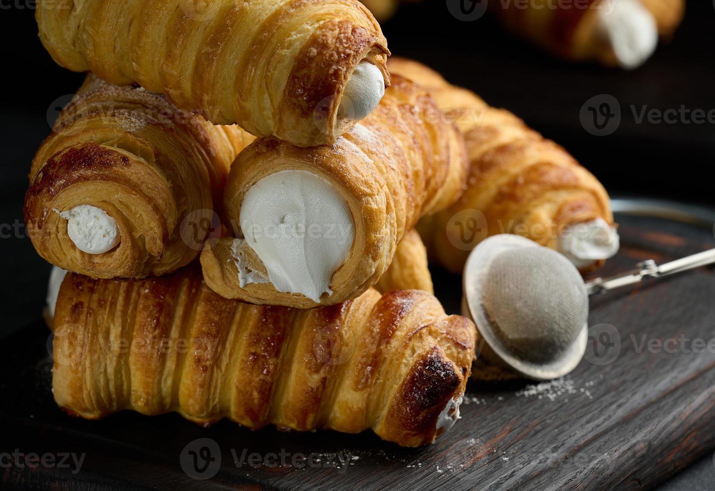 al forno tubuli pieno con frustato uovo bianchi crema su un' nero di legno cucina tavola foto