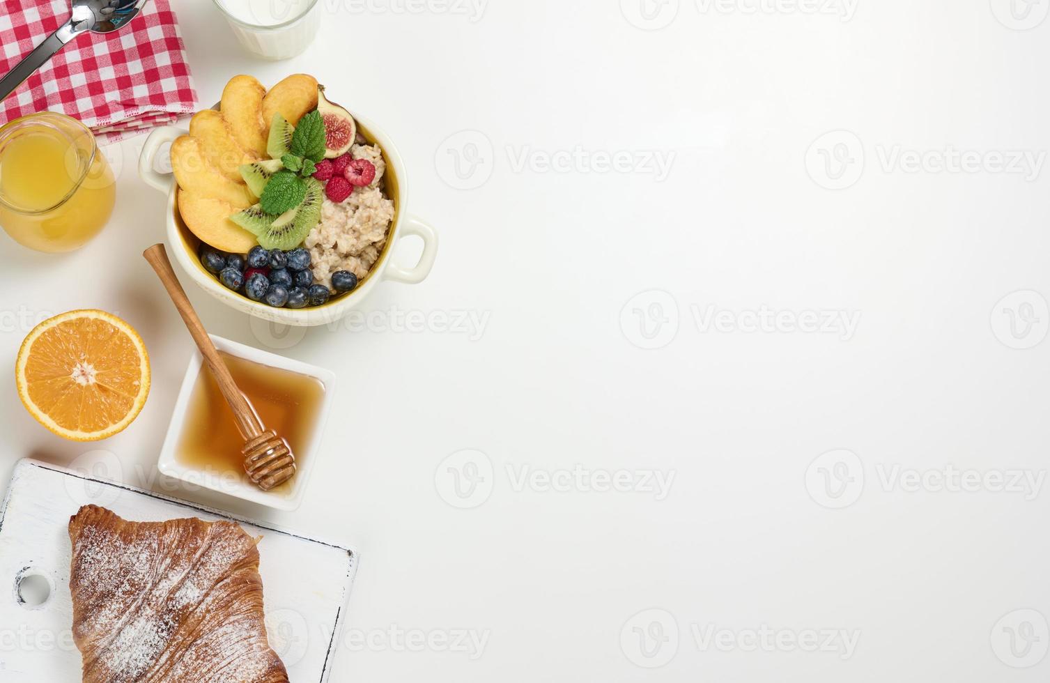 latte, piatto con fiocchi d'avena porridge e frutta, appena spremuto succo nel un' trasparente bicchiere decantatore, miele foto