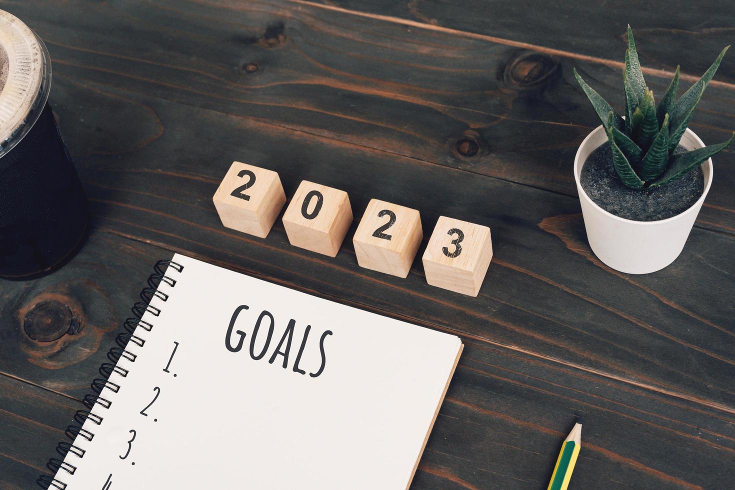 2023 obiettivi testo su bloc notes con caffè tazza e penna su di legno scrivania foto