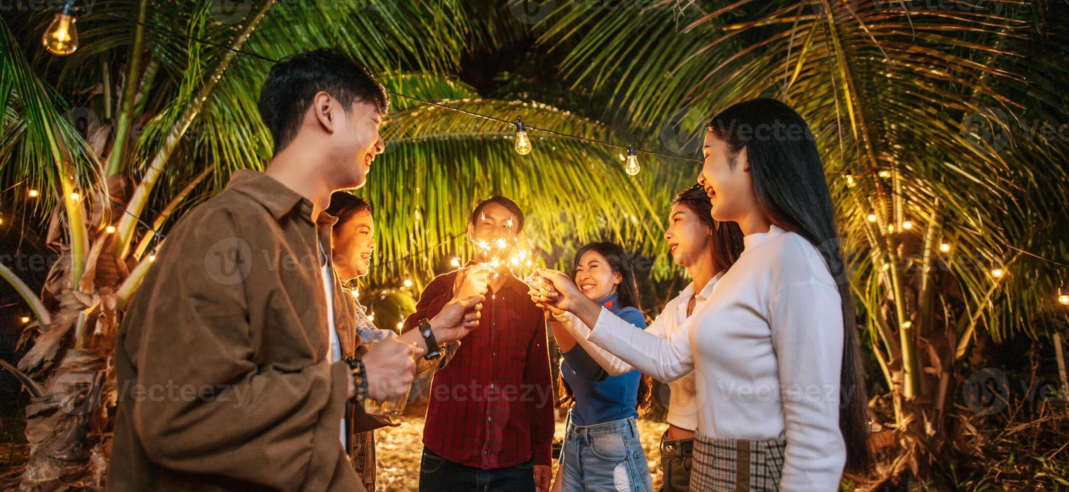 ritratto di contento asiatico gruppo di amici avendo divertimento con sparklers all'aperto - giovane persone avendo divertimento con fuochi d'artificio a notte tempo - le persone, cibo, bevanda stile di vita, nuovo anno celebrazione concetto. foto