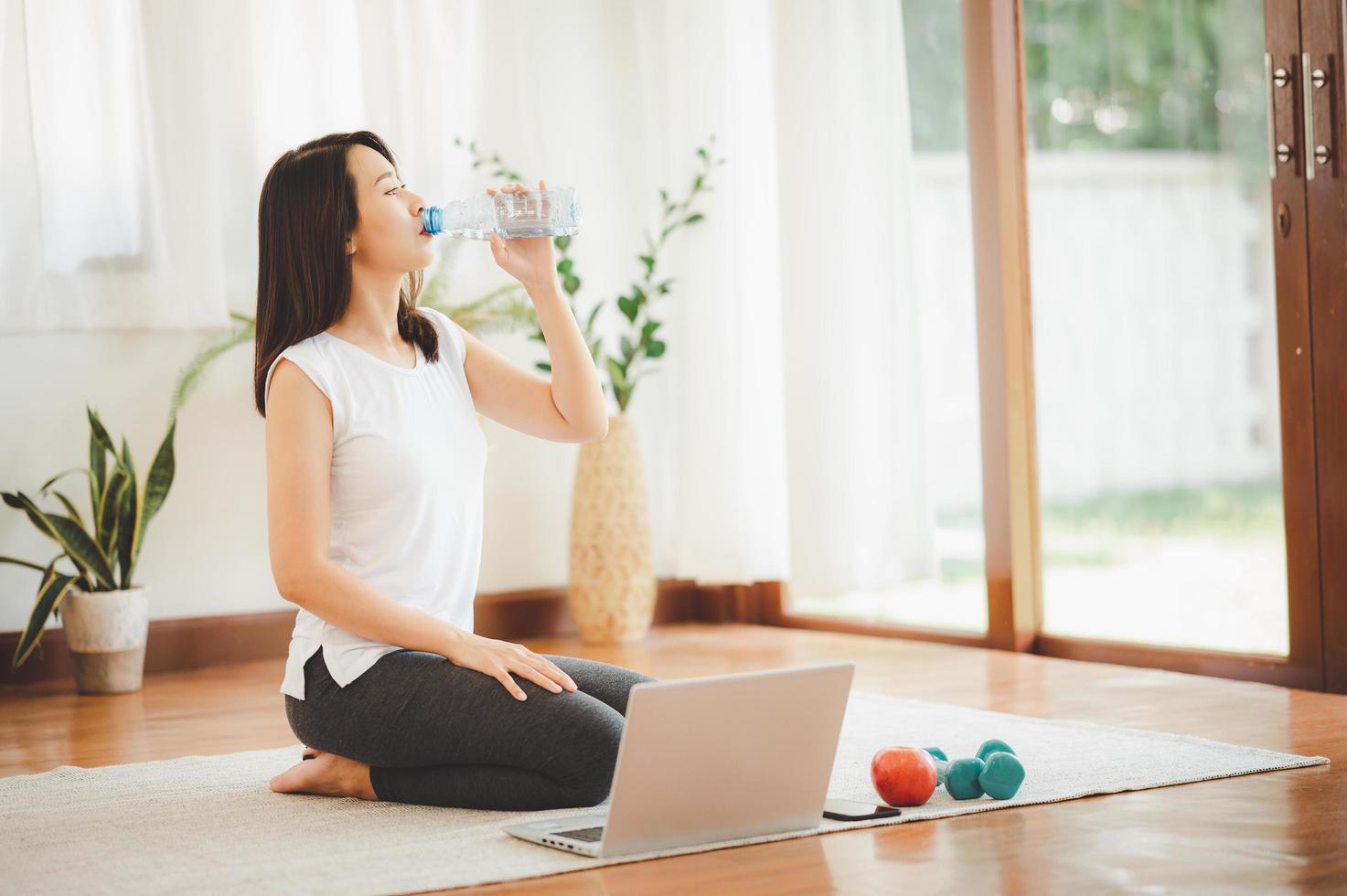 donna che beve acqua mentre si fa allenamento virtuale foto