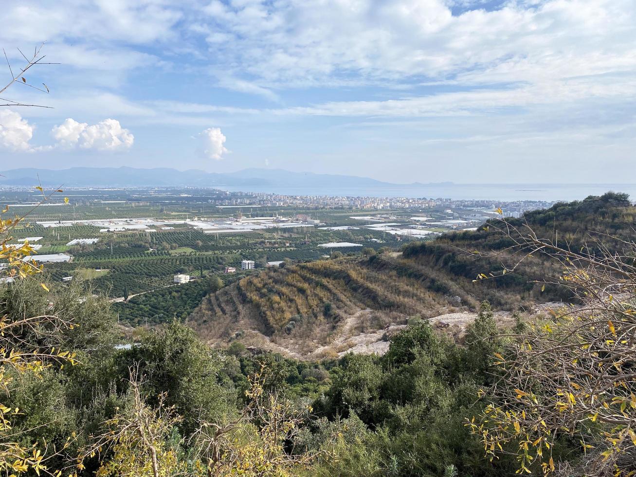 panoramico paesaggio di edifici nel un urbano cittadina lungo il montagna e mare su un' soleggiato giorno. un' Visualizza a partire dal il mare. foto