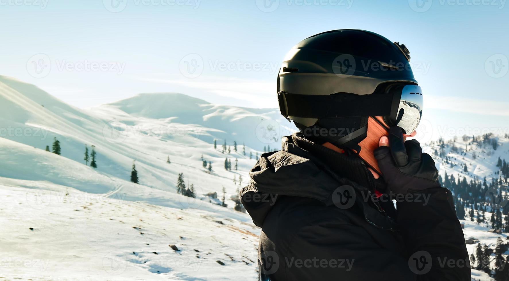 eccitato sciatore uomo nel nero giacca sciare occhiali maschera testo amici tiro su mobile Telefono trascorrere fine settimana inverno nel montagne isolato su viola sfondo. persone stile di vita passatempo concetto foto