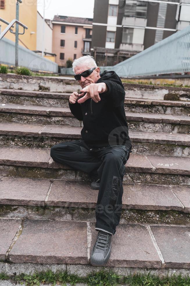 maturo uomo rap cantante in posa su le scale all'aperto su il sobborgi di un' città foto