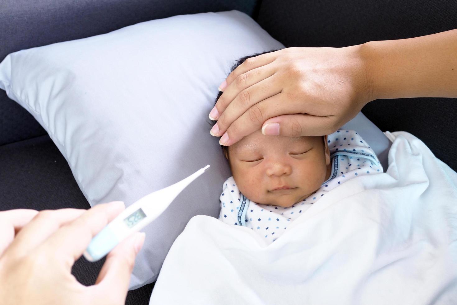 malato bambino dire bugie su il divano madre toccare corpo e Usato il termometro per dai un'occhiata il temperatura. foto