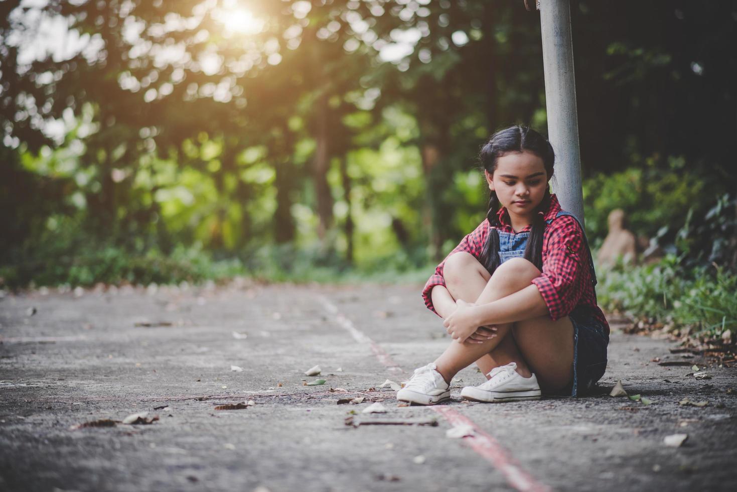 ragazza triste che si siede in un parco foto