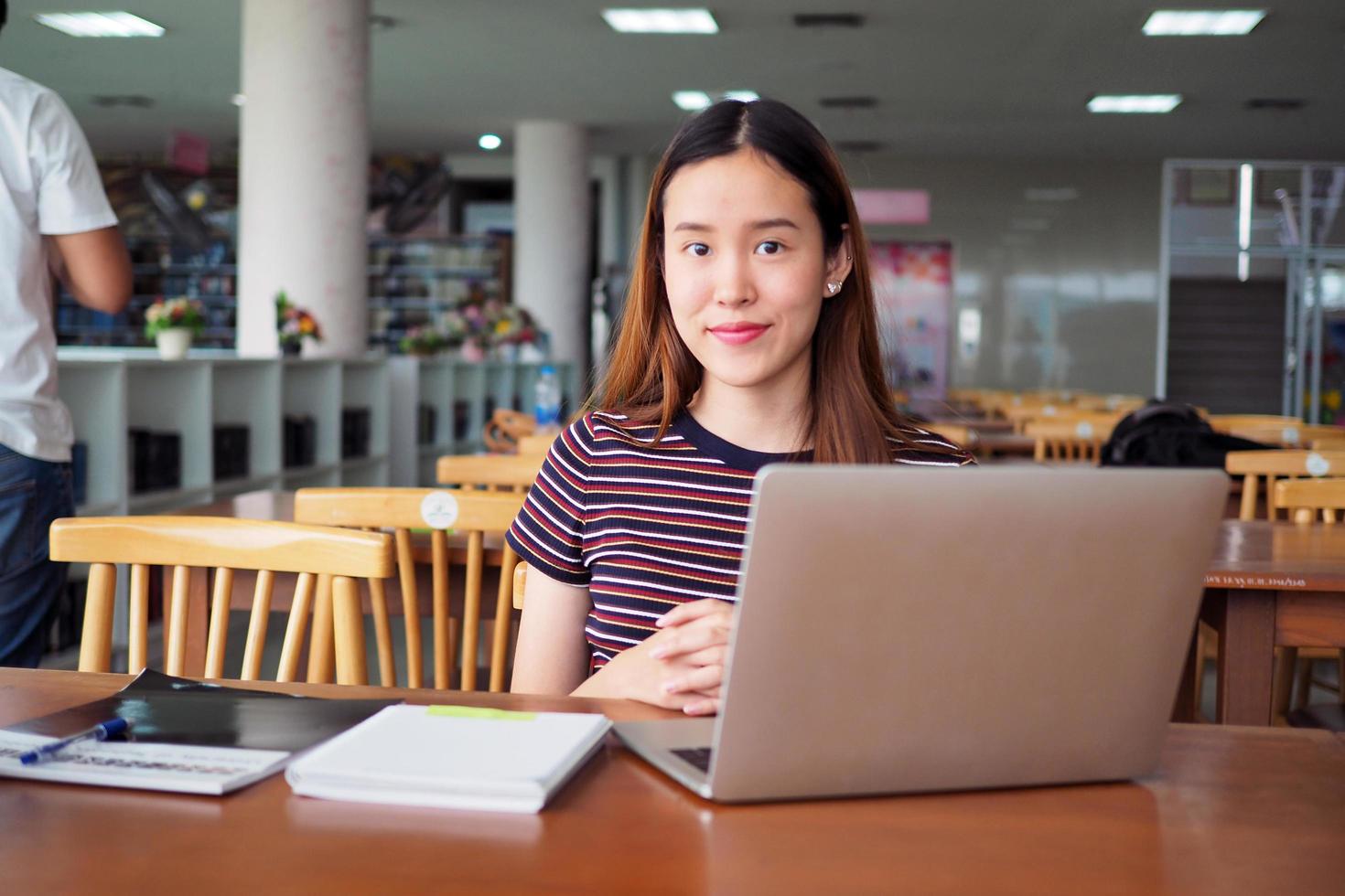 asiatico studenti siamo nel il Università biblioteca con computer e libri. foto