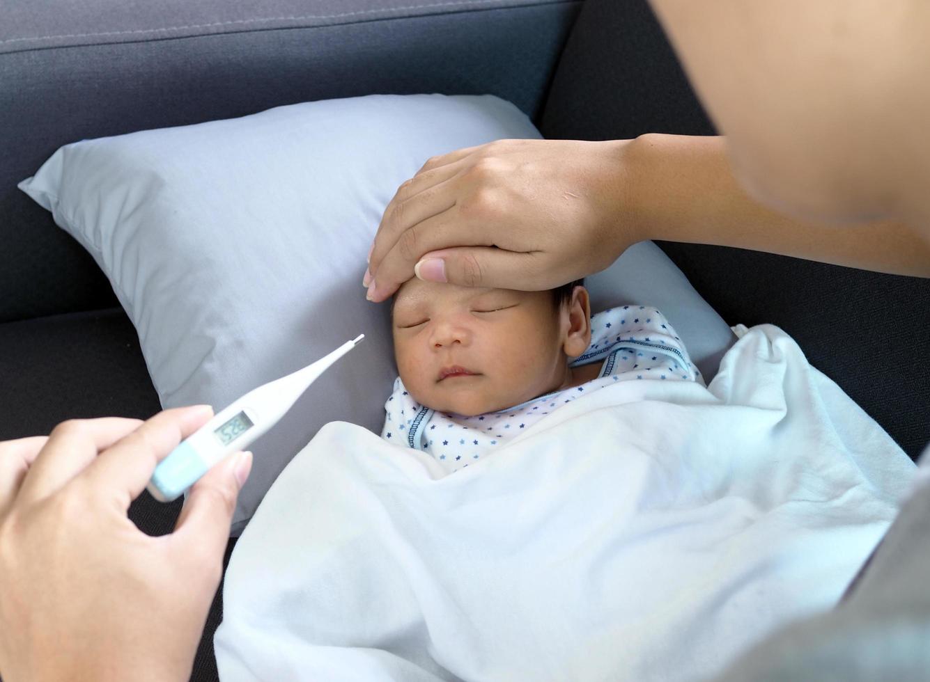 malato bambino dire bugie su il divano madre toccare corpo e Usato il termometro per dai un'occhiata il temperatura. foto