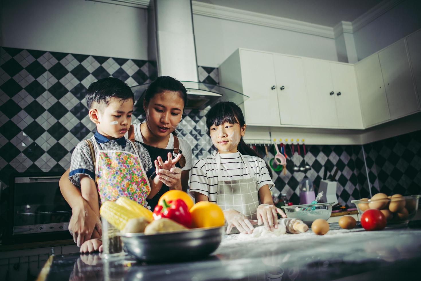 la mamma insegna ai suoi figli come preparare l'impasto della pizza foto