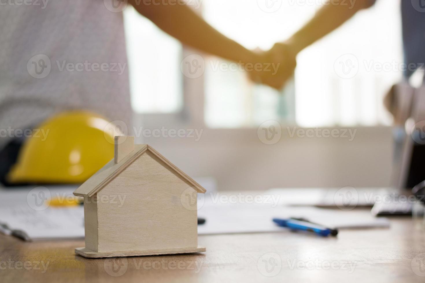 due persone si stringono la mano e costruiscono una casa foto