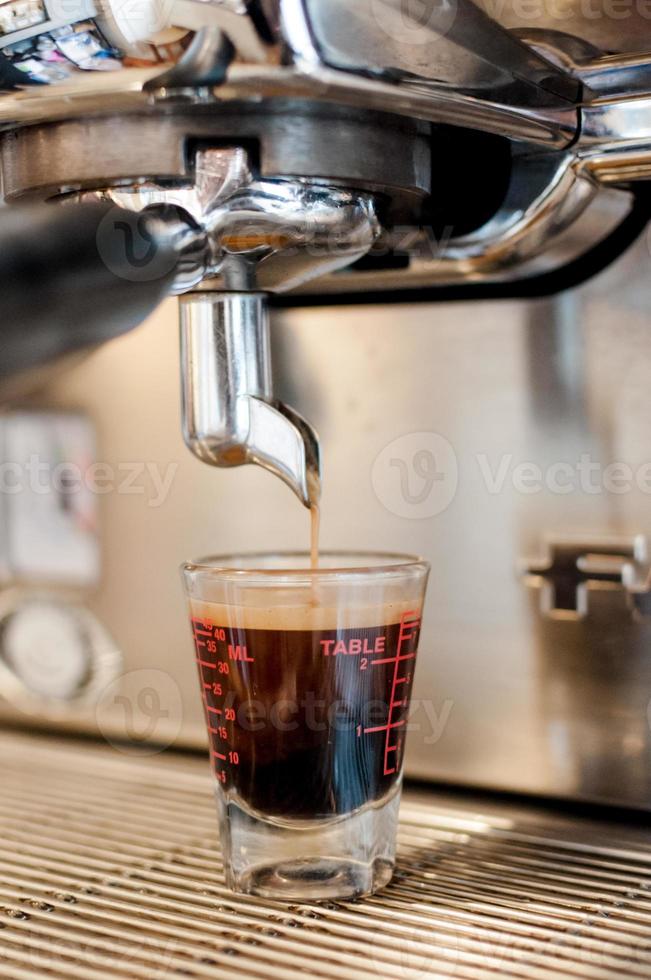 avvicinamento nero caffè nel misurazione tazza mettere su caffè creatore, caffè macchina fabbricazione caffè espresso foto