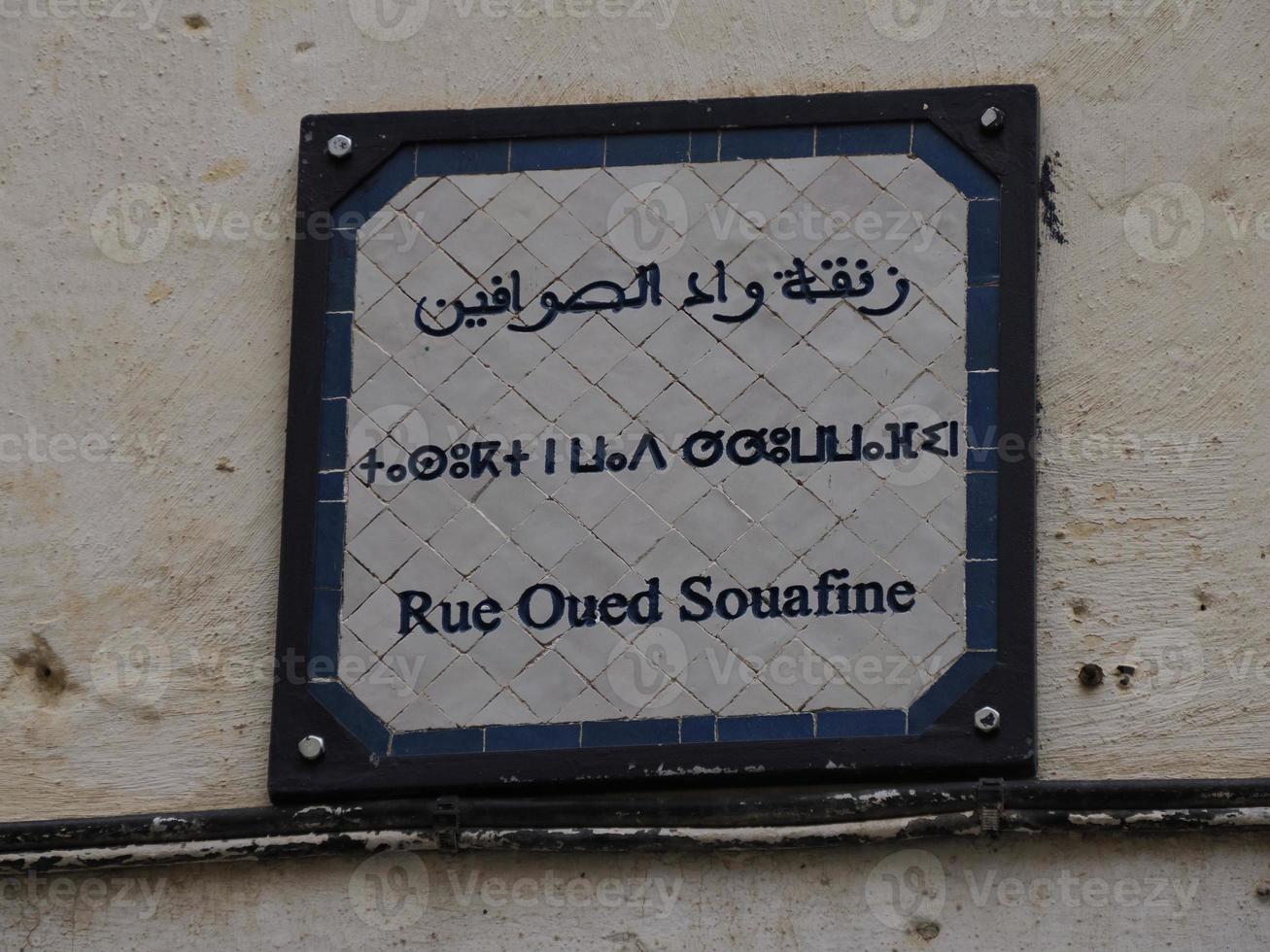 piccolo strada cartello tri linguale Arabo francese e berbero nel fez medina vecchio cittadina. Marocco. foto