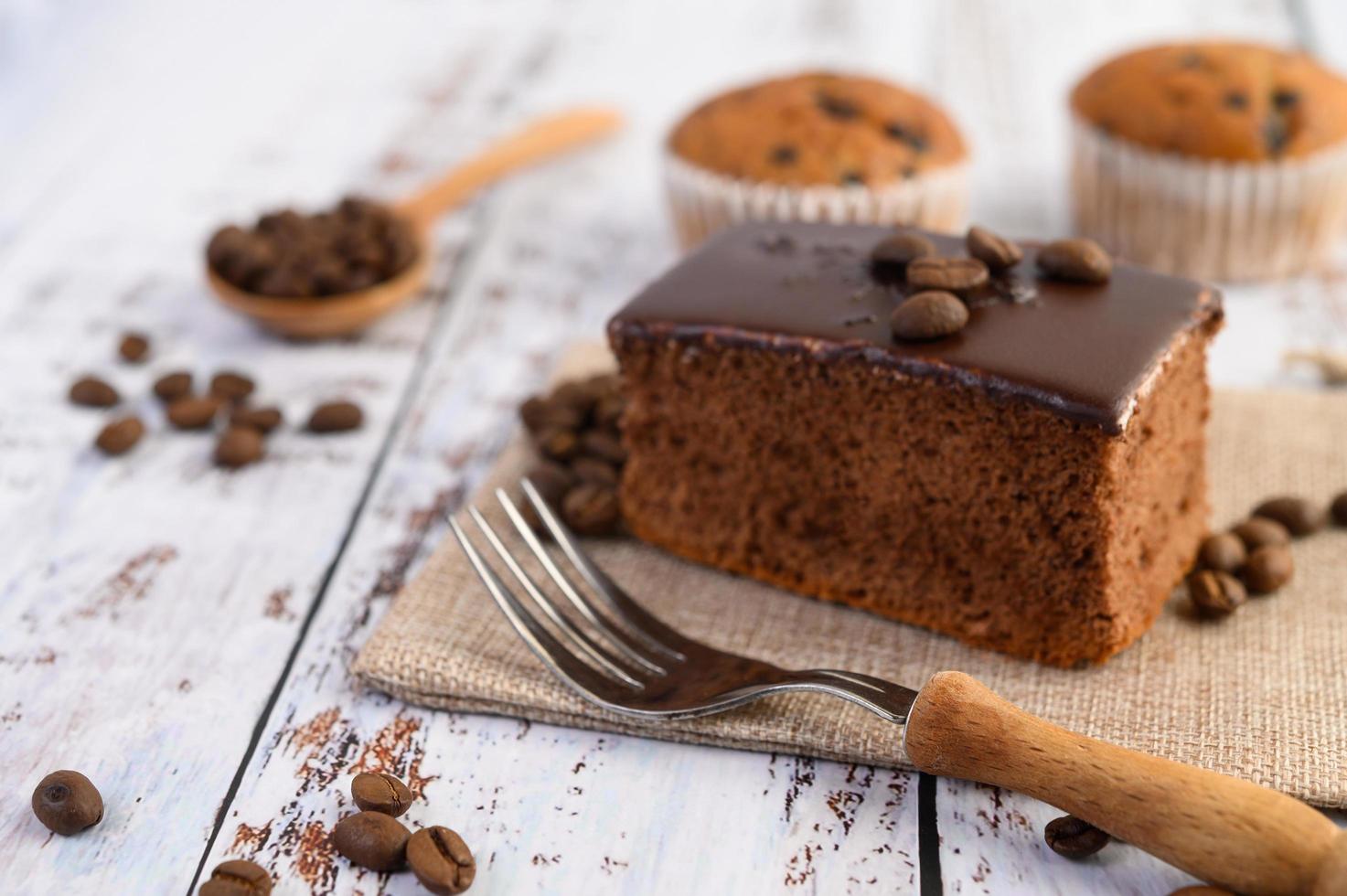 torta al cioccolato sul sacco e chicchi di caffè con forchetta su un tavolo di legno. foto