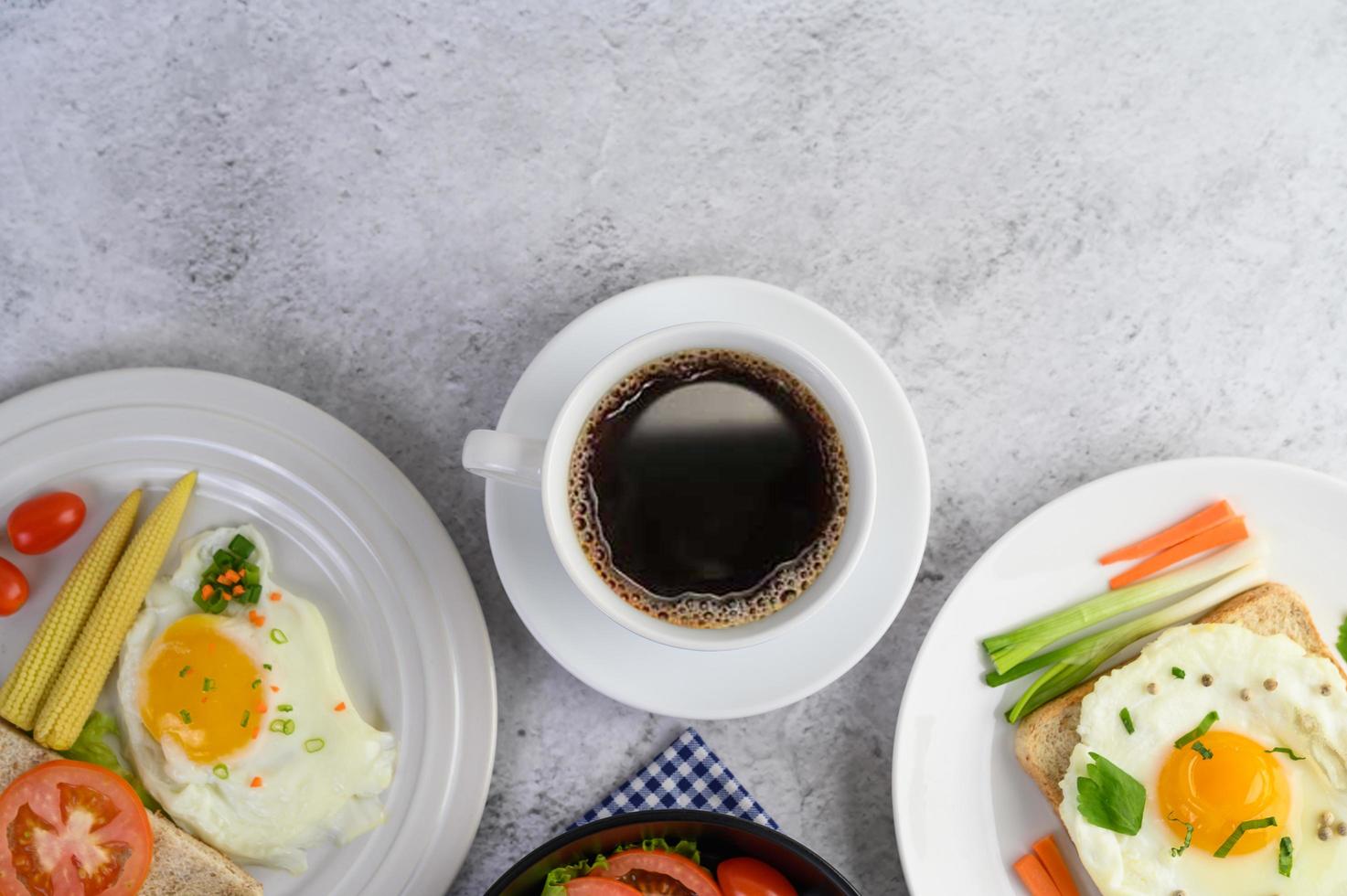 uova sode, carote e pomodori con cucchiaio e tazza di caffè foto